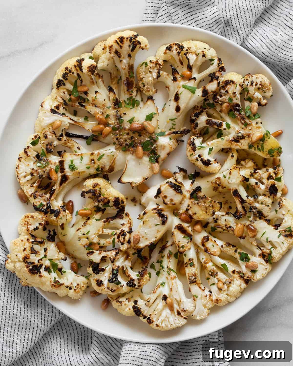 Zesty Grilled Cauliflower Steaks 2 Perfectly grilled lemon pepper cauliflower steaks arranged artfully on a serving plate, garnished with fresh herbs.