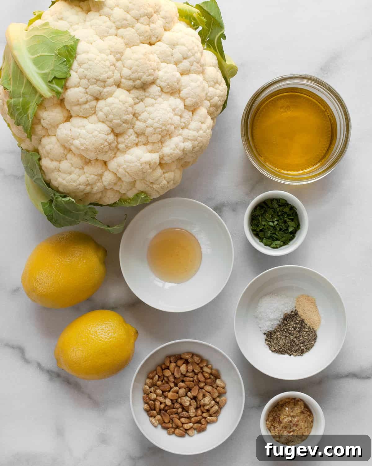 Zesty Grilled Cauliflower Steaks 3 An array of fresh ingredients including a head of cauliflower, vibrant lemons, olive oil, honey, mustard, various spices, and fresh parsley, all ready for the recipe.