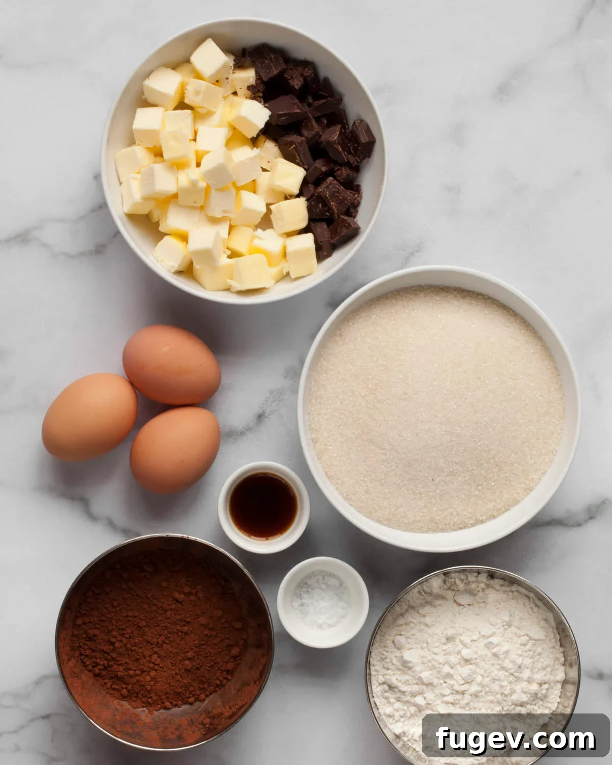 Effortless Salted Fudge Brownies 3 A flat lay of brownie ingredients including chocolate, butter, sugar, cocoa powder, eggs, flour, and vanilla extract.