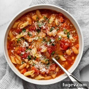 A bowl of creamy, rich Pasta e Fagioli soup, garnished with fresh herbs, ready to be served.