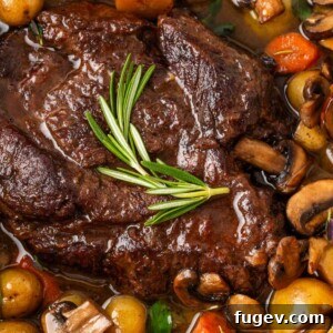 Close-up of a rustic pot roast in a Dutch oven with vibrant vegetables.
