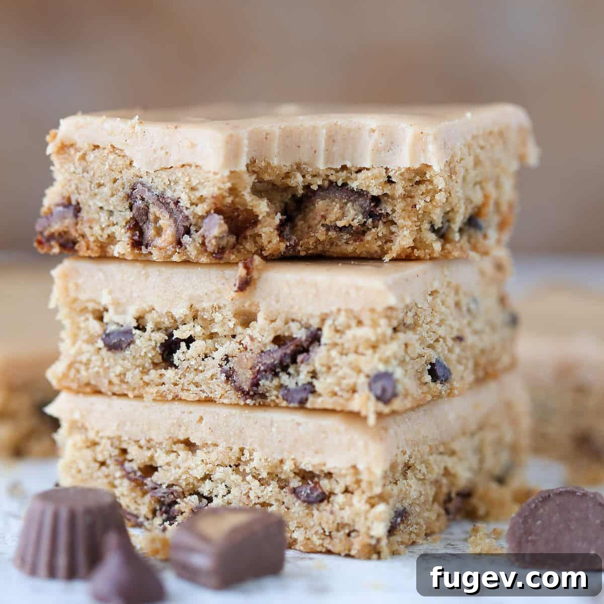 Peanut Butter Chocolate Swirl Blondies 2 Reeses Peanut Butter Blondies bitten, showcasing a perfect chewy texture and generous mix-ins, topped with creamy peanut butter icing.