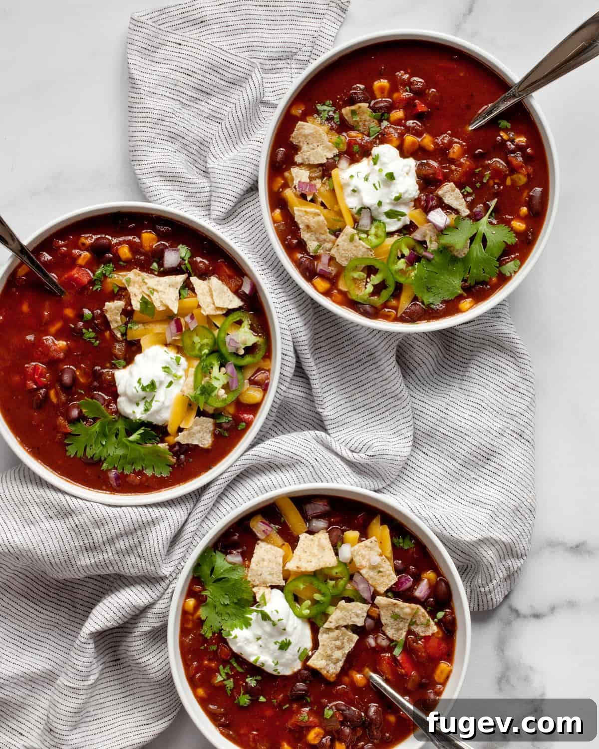 Savory Black Bean Sensation 2 Three bowls of black bean chili with various toppings like shredded cheese, sour cream, cilantro, and jalapeños.