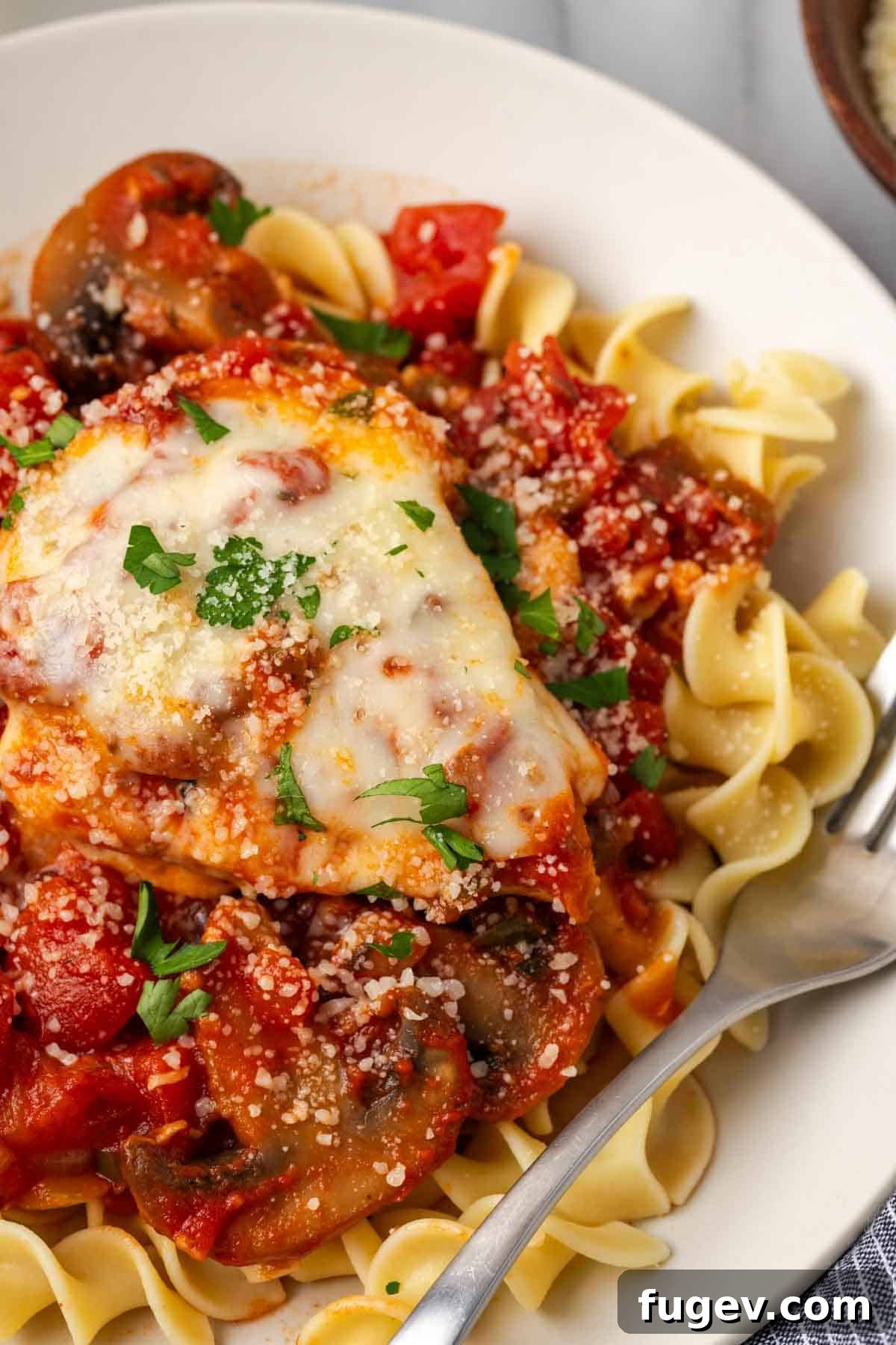Hearty Marinara Chicken Bake 12 marinara chicken on a plate with noodles and sauce, ready to be eaten.