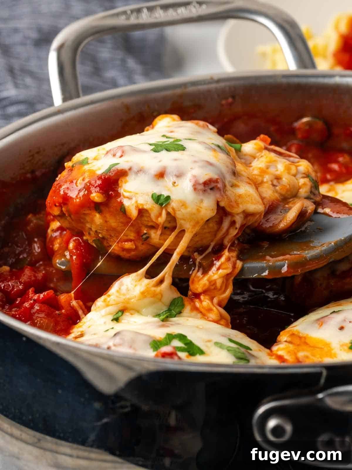 Hearty Marinara Chicken Bake 3 cheese pull from a chicken breast in tomato sauce, highlighting its meltiness.