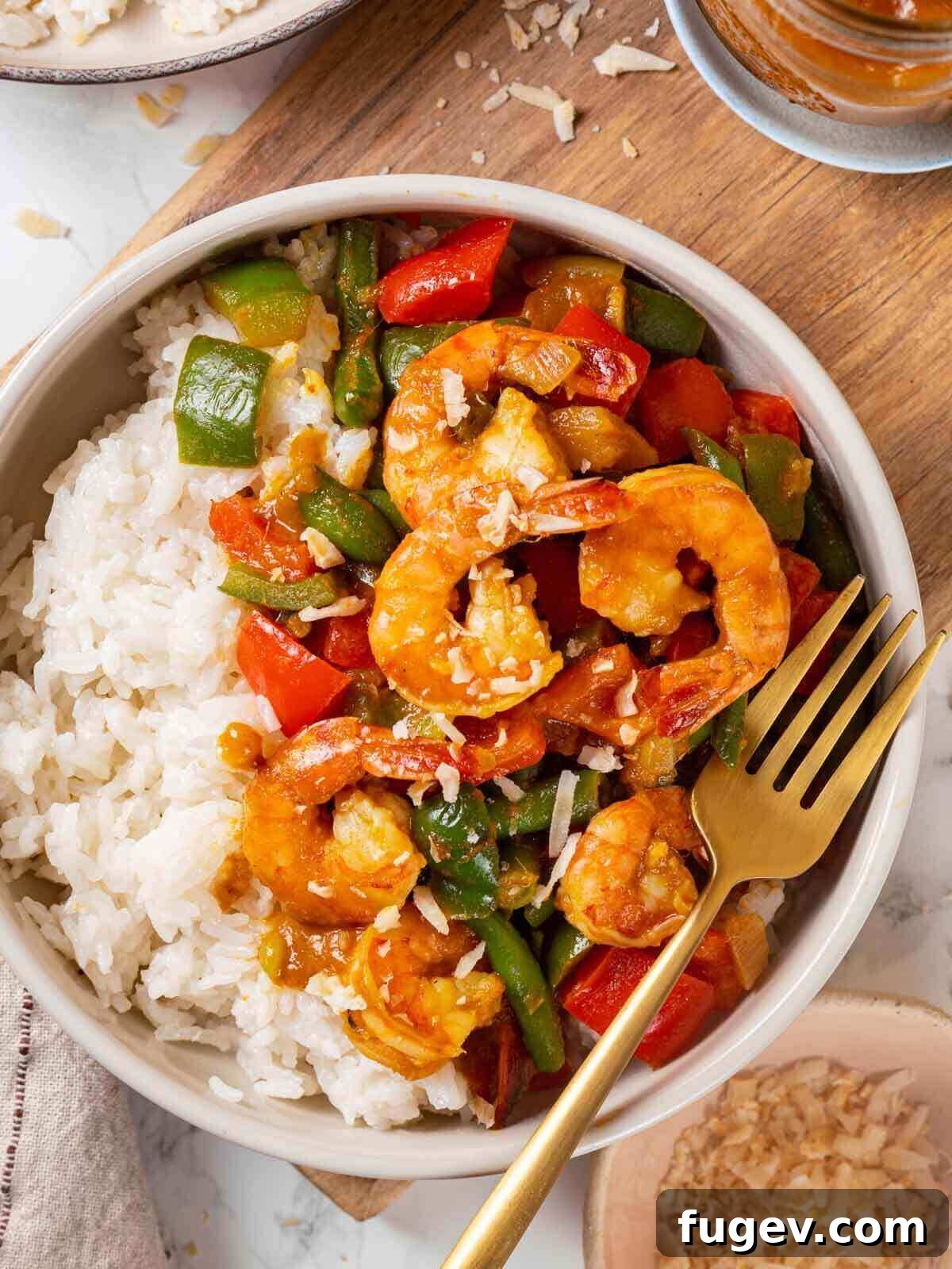 Aromatic Golden Prawns 2 A vibrant bowl of shrimp curry served alongside a portion of coconut rice on a rustic wooden table, garnished with fresh herbs, ready to be enjoyed.