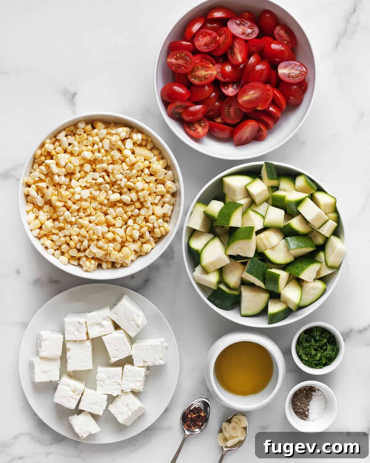 Tek Tepside Fırınlanmış Feta ve Sebzeler 3 A collection of fresh ingredients: feta cheese, zucchini, corn, tomatoes, olive oil, garlic, parsley, red pepper flakes, salt, and pepper.