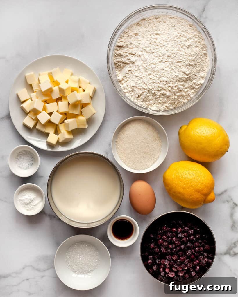 Zesty Lemon Blueberry Scones 3 A flat lay of ingredients for lemon blueberry scones including flour, cold butter, sugar, lemons, blueberries, baking powder, egg, vanilla extract, and salt.