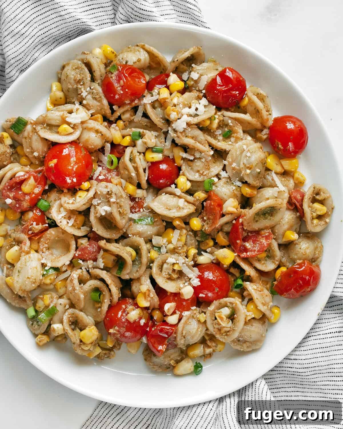 Summer Harvest Orecchiette 7 A serving of easy tomato corn pasta on a white plate, garnished with fresh basil leaves.