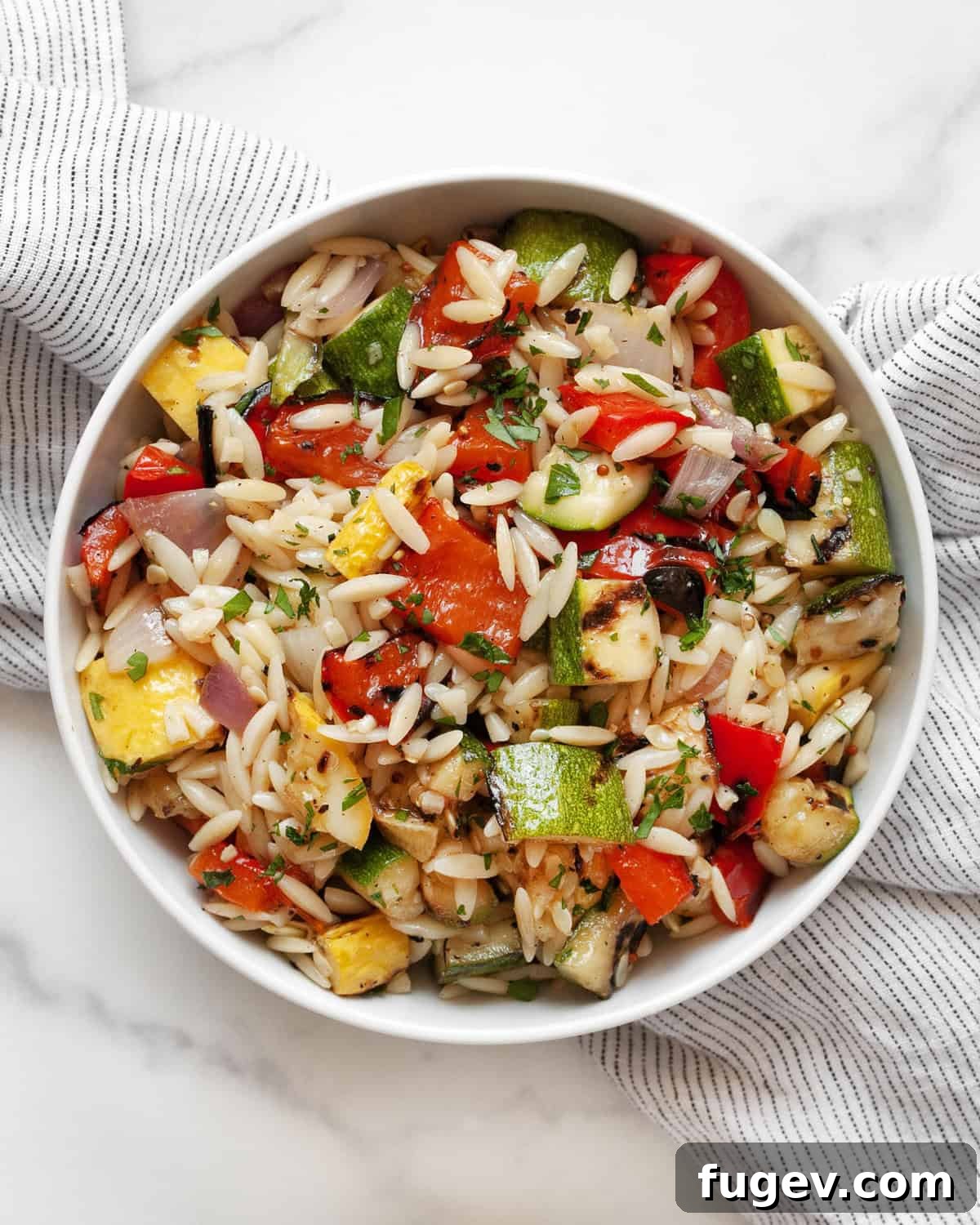 Smoky Garden Orzo Salad 8 A small serving bowl filled with a delightful grilled vegetable orzo salad, perfectly garnished.