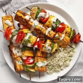 Grilled tofu and vegetable skewers with couscous on a plate.