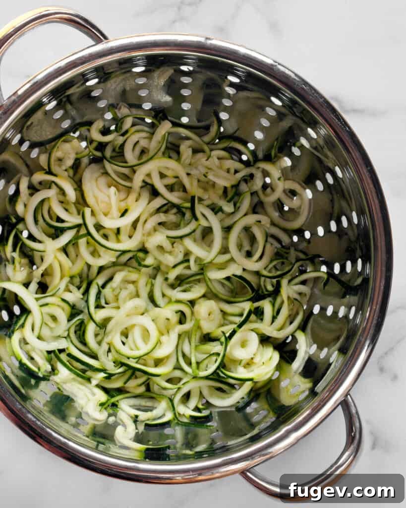 Fresh Zucchini Cacio e Pepe 7 Salted zucchini noodles draining in a colander, ready for squeezing.