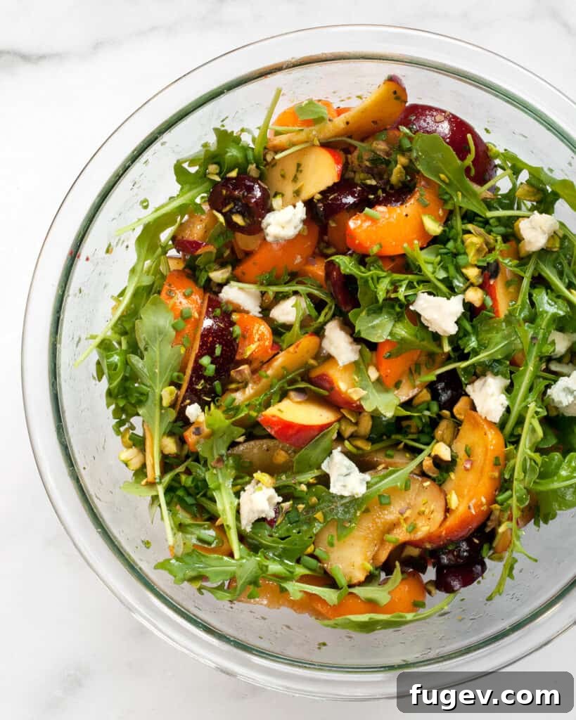 Summer Stone Fruit Salad with Creamy Gorgonzola and Zesty Pesto Vinaigrette 6 Mixing bowl with stone fruit, greens, cheese, and vinaigrette being tossed together