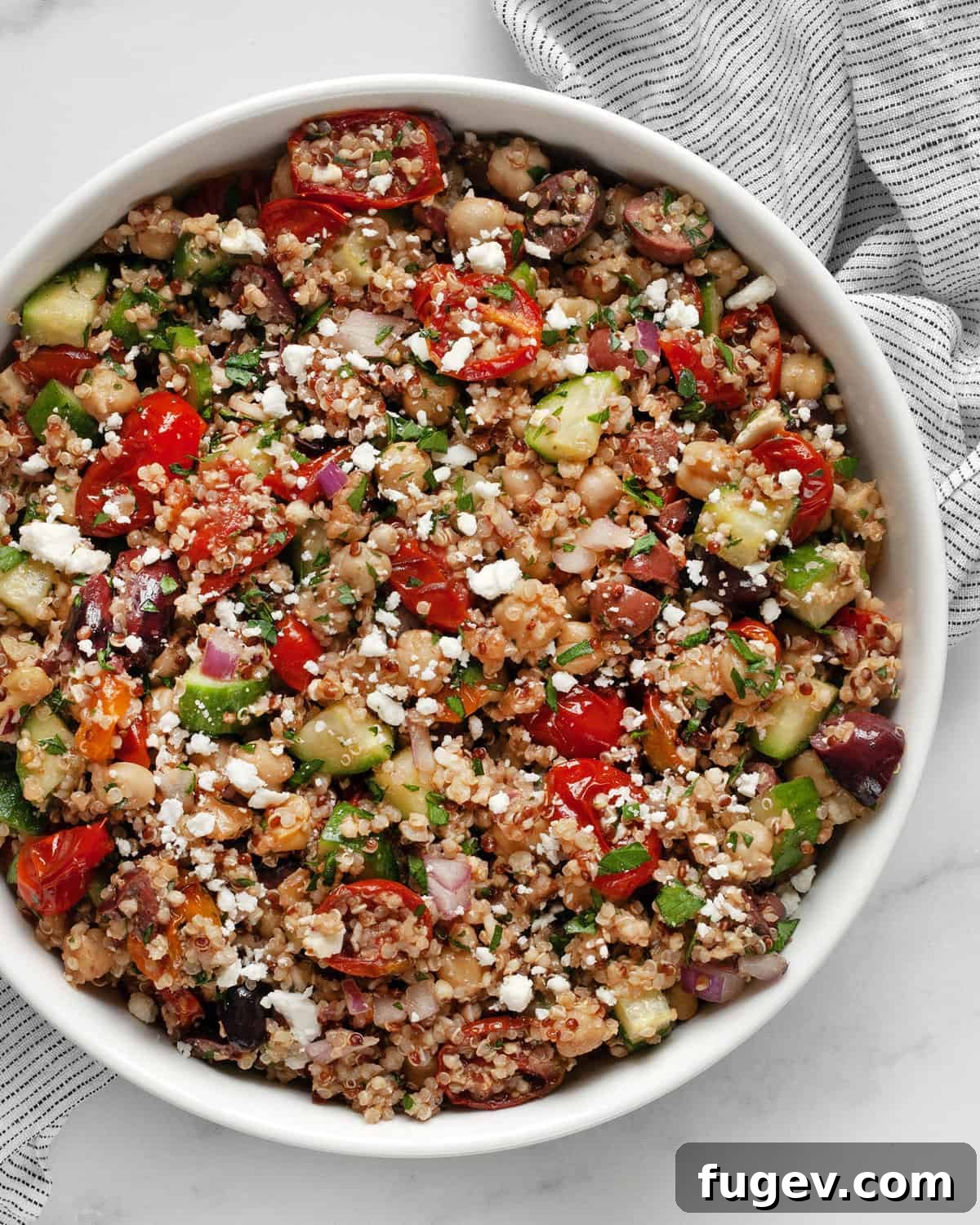 Roasted Tomato Quinoa and Chickpea Medley 7 A serving bowl overflowing with roasted tomato, chickpea quinoa salad, garnished with fresh parsley and feta.