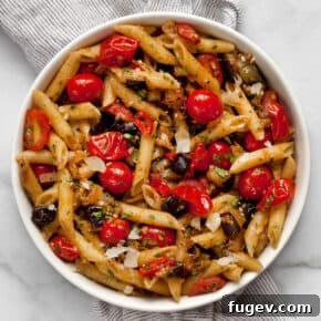 Penne pasta dish featuring tender sautéed eggplant and burst cherry tomatoes, infused with chili and garlic.