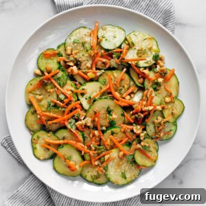 Cucumber carrot salad on a plate, garnished with fresh herbs and chopped peanuts.