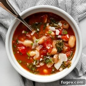 White bean tomato soup with fresh rosemary and a drizzle of olive oil in a bowl.