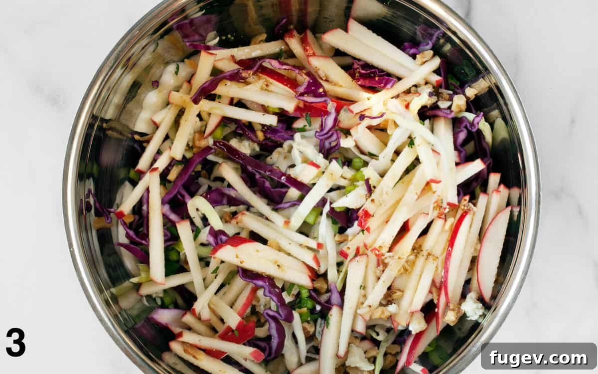 Tossed Apple Cabbage Salad Apple Cabbage Salad fully tossed with vinaigrette in a serving bowl.