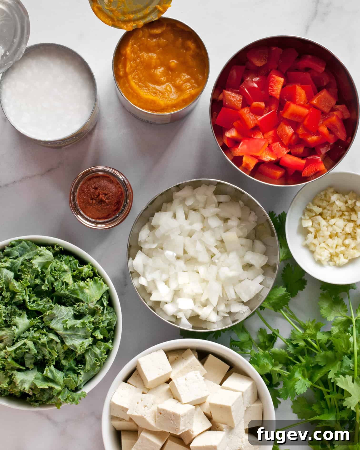Golden Vegan Pumpkin Curry 3 Ingredients for vegan tofu curry with pumpkin, including tofu, pumpkin puree, red curry paste, coconut milk, onions, red peppers, garlic, ginger, kale, cilantro, and lime.