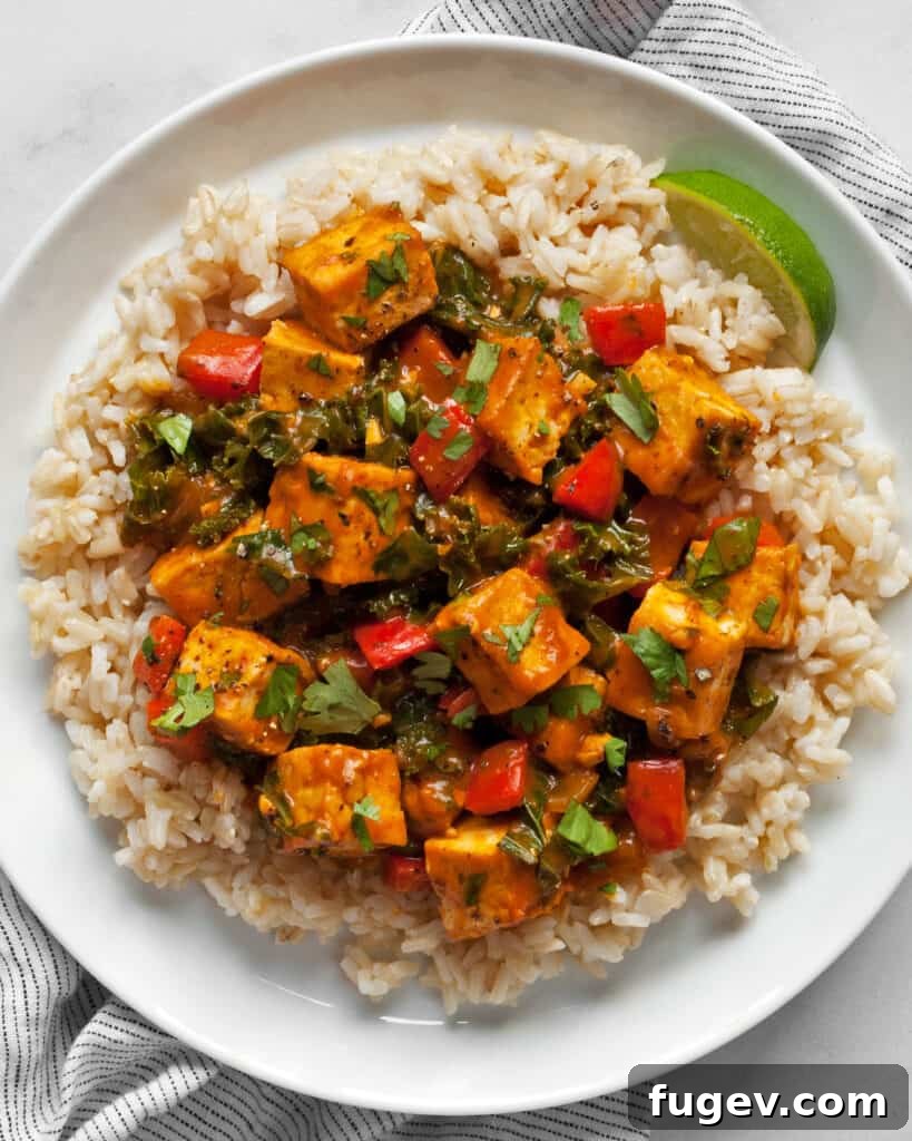 Golden Vegan Pumpkin Curry 8 A bowl of Tofu Pumpkin Curry with Rice, garnished with fresh cilantro and lime