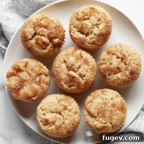 Seven apple muffins on a plate.