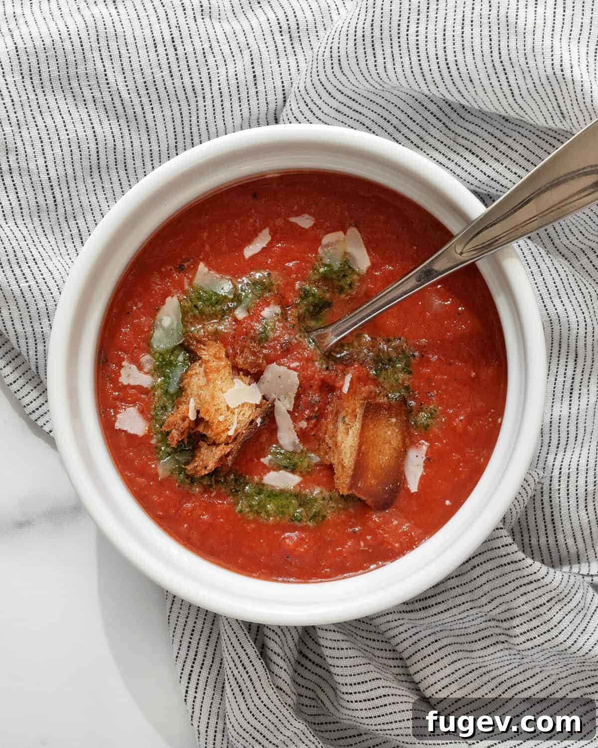 Pantry-Powered Roasted Tomato Soup 2 A steaming bowl of rich roasted tomato soup, garnished with fresh basil, Parmesan cheese, and golden croutons.