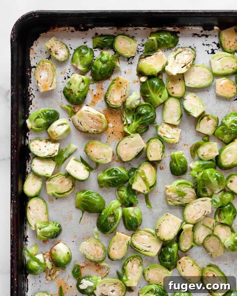 Sticky Sweet Heat Brussels Sprouts 6 Brussels sprouts tossed with sriracha marinade on a sheet pan, ready for the oven