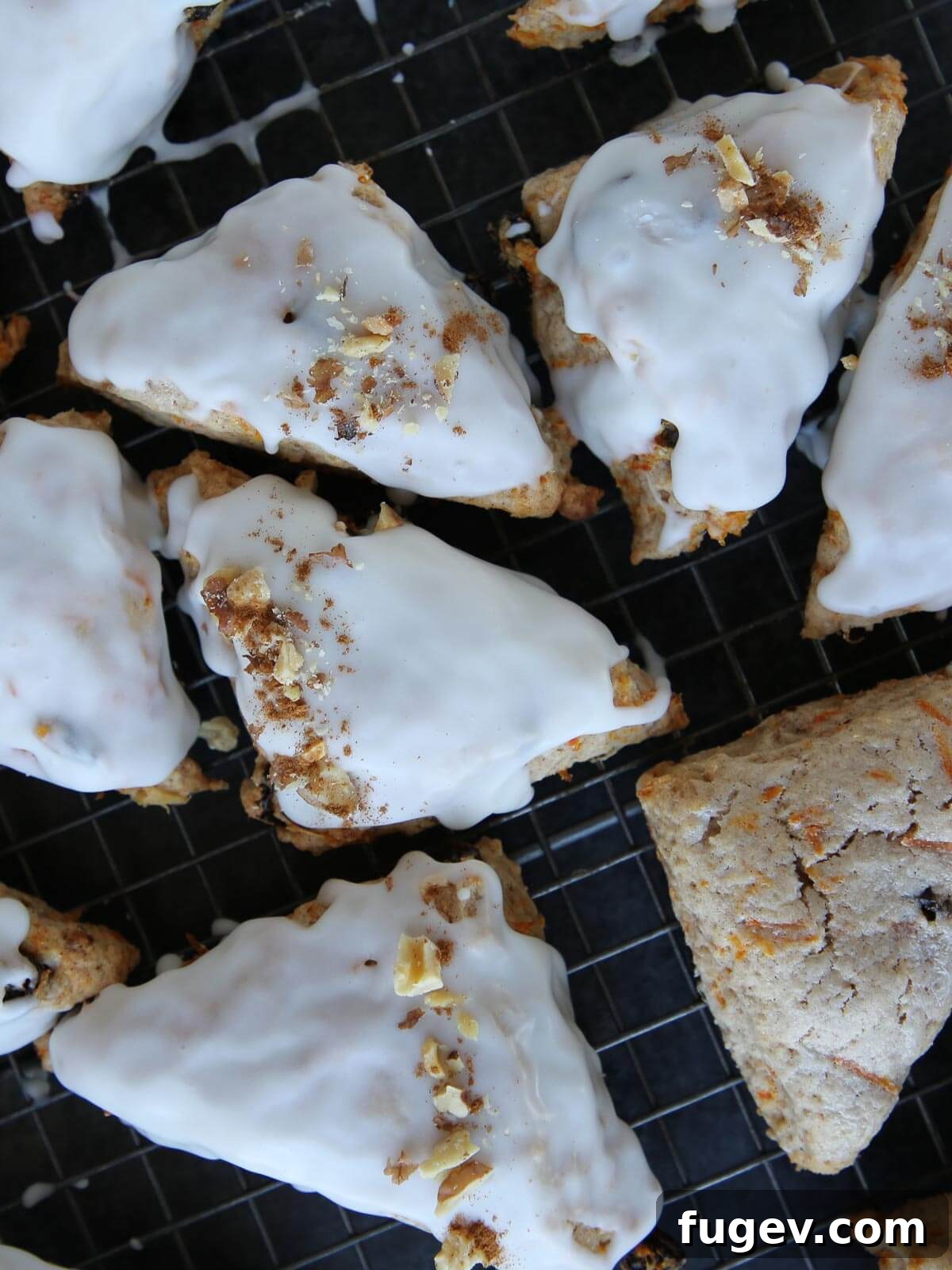 Spiced Carrot Scones 4 Freshly baked carrot cake scones cooling on a wire rack, with some glaze beginning to harden.