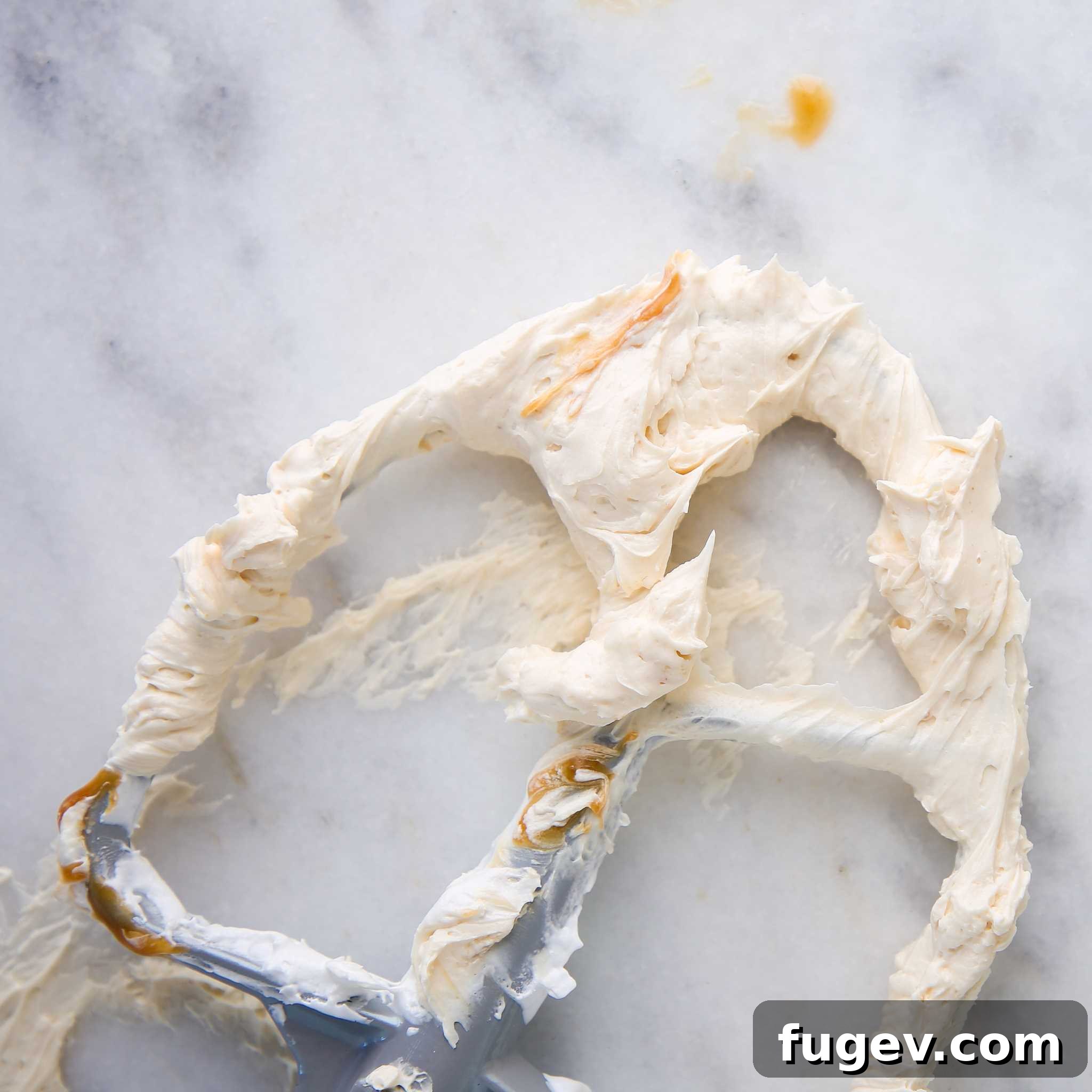 Caramel Swiss Meringue Buttercream delicately spread on a marble slab, highlighting its smooth and luxurious consistency.