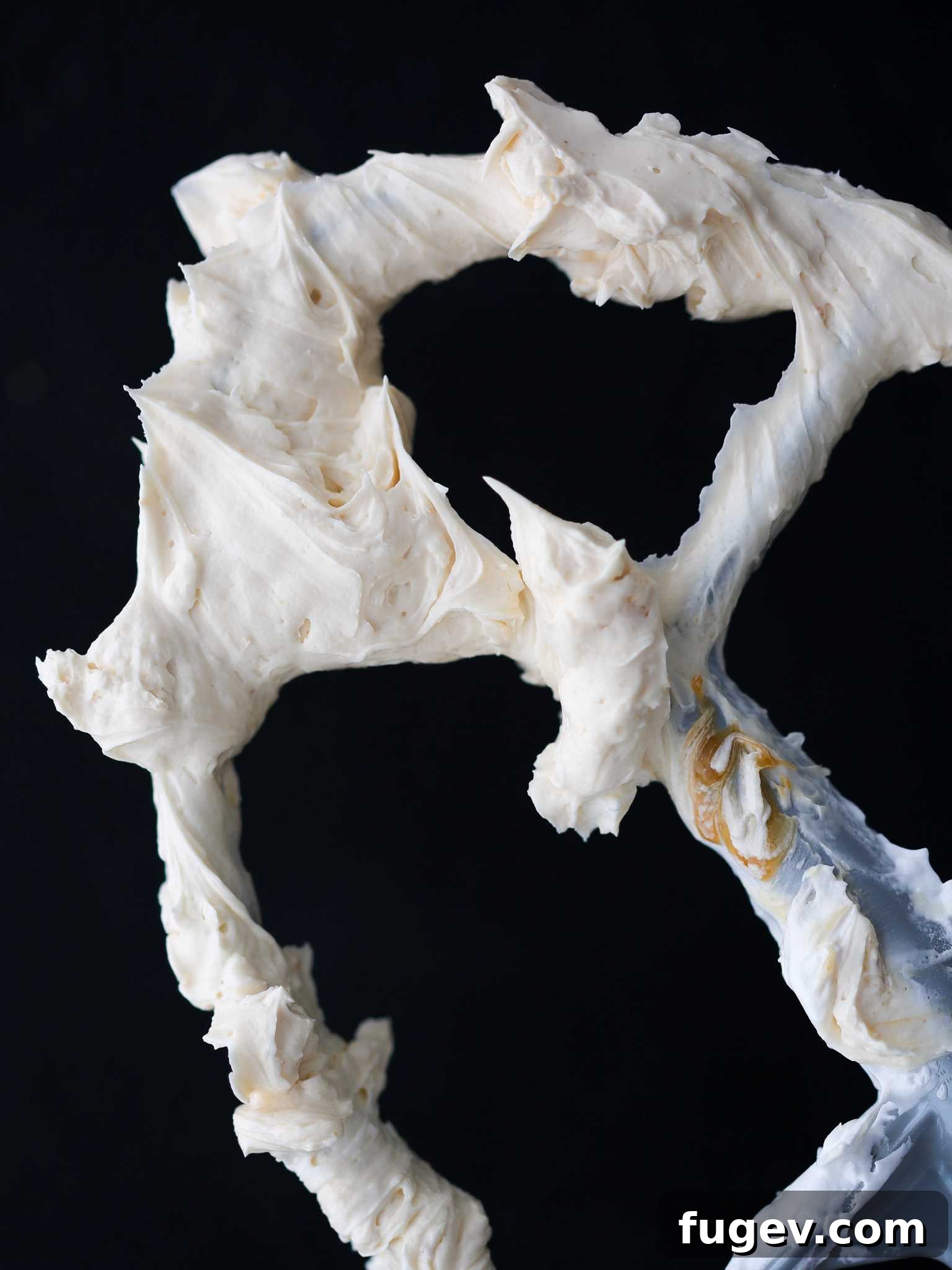 Caramel Swiss Meringue Buttercream on a paddle attachment of a stand mixer, showing its creamy consistency.