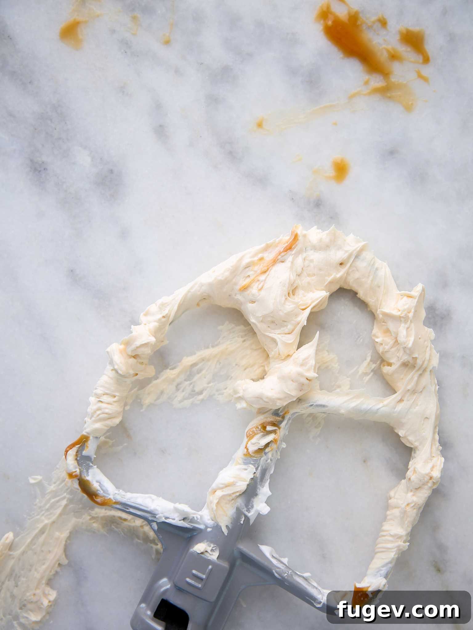 Caramel Swiss Meringue Buttercream dolloped on a clean white background, highlighting its rich color and texture.
