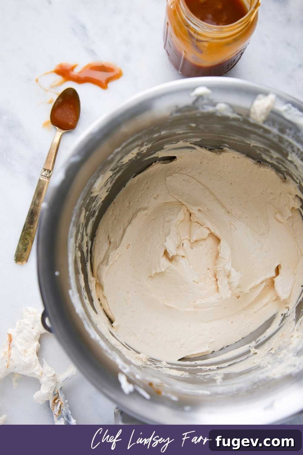 A jar of golden salted caramel sauce, hinting at the key flavor of the Swiss Meringue Buttercream.