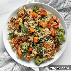 Roasted butternut squash and broccoli orzo on a plate, garnished with fresh herbs.