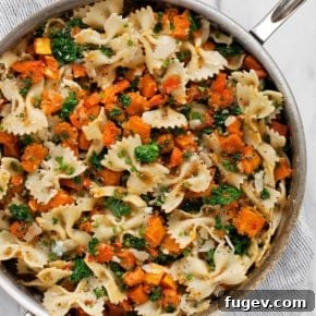 Squash pasta in a skillet, featuring bowtie pasta, kale, and roasted butternut squash.