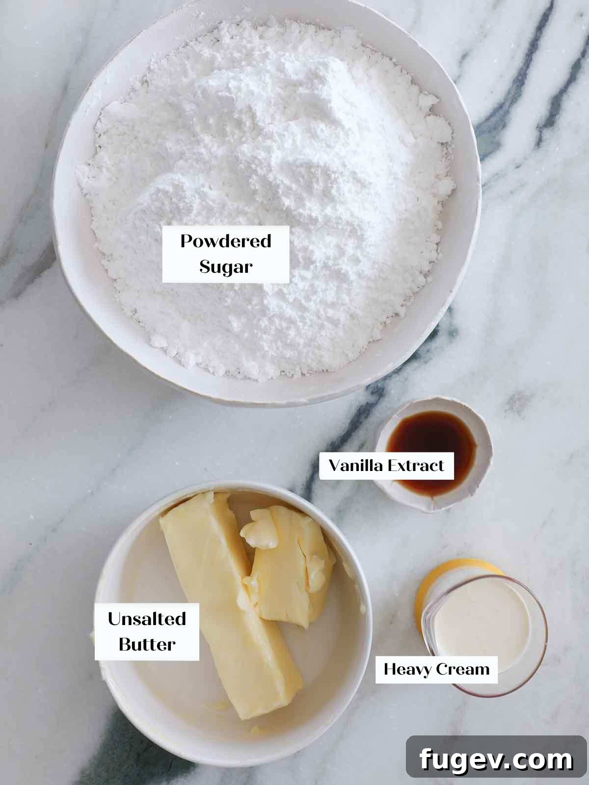 The Ultimate American Buttercream Recipe 4 Four key ingredients for American buttercream laid out on a marble surface: butter, powdered sugar, vanilla extract, and heavy cream.