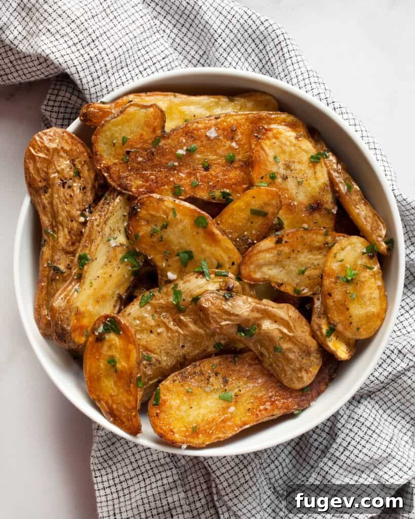 Golden Garlic Herb Fingerling Potatoes 5 A bowl of Garlic Herb Roasted Fingerling Potatoes, perfectly golden and garnished with fresh herbs.