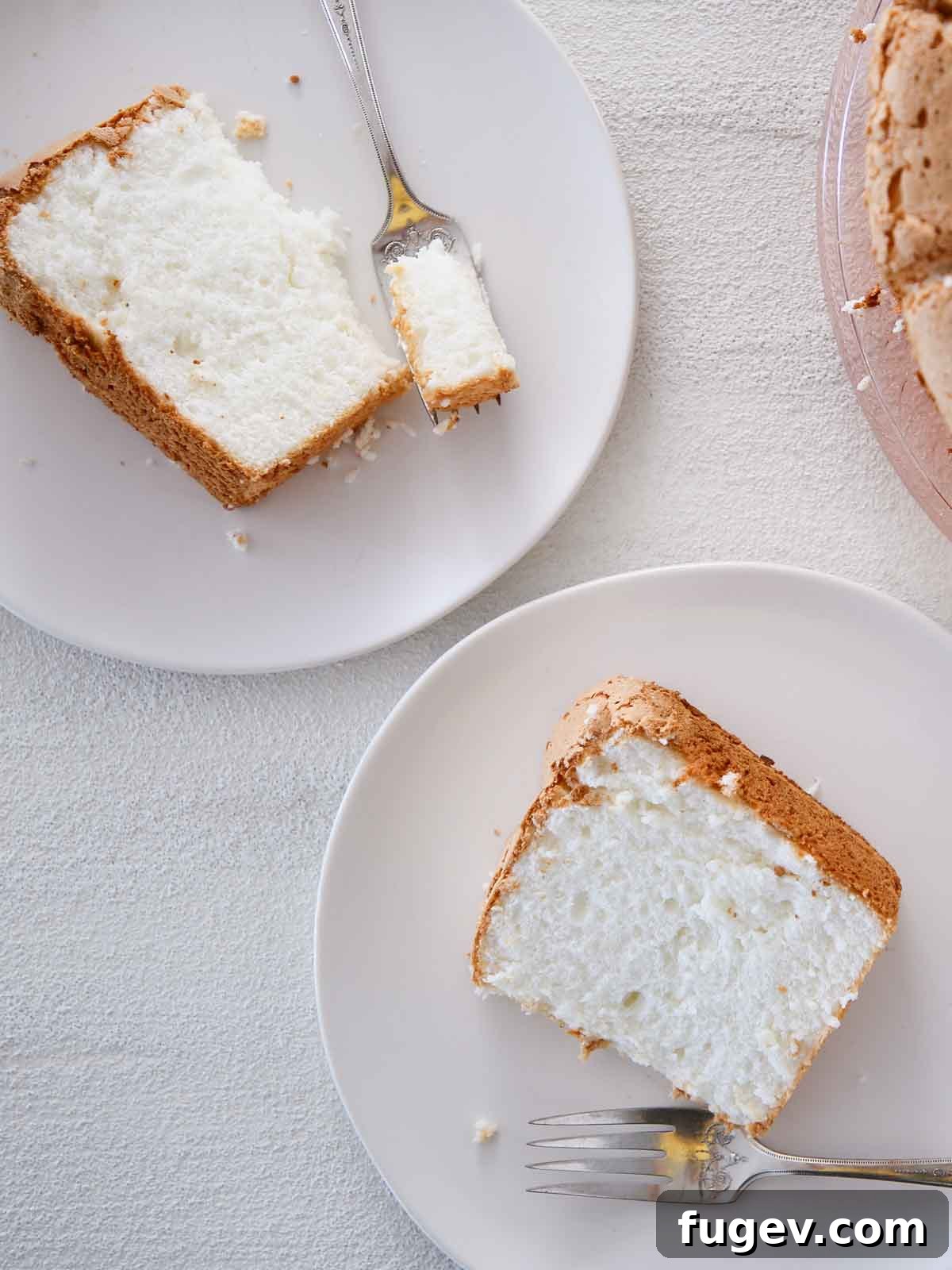 Heavenly Cloud Delight 2 White angel food cake slices served on elegant white plates against a pristine white background, showcasing its delicate texture.
