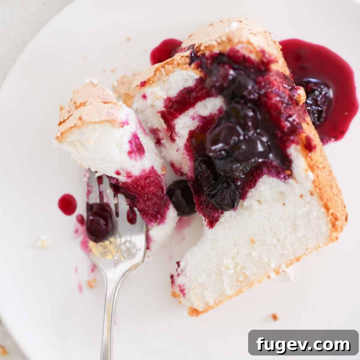Heavenly Cloud Delight 5 A delectable slice of angel food cake with a small bite taken from it by a fork, highlighting its soft, airy texture.