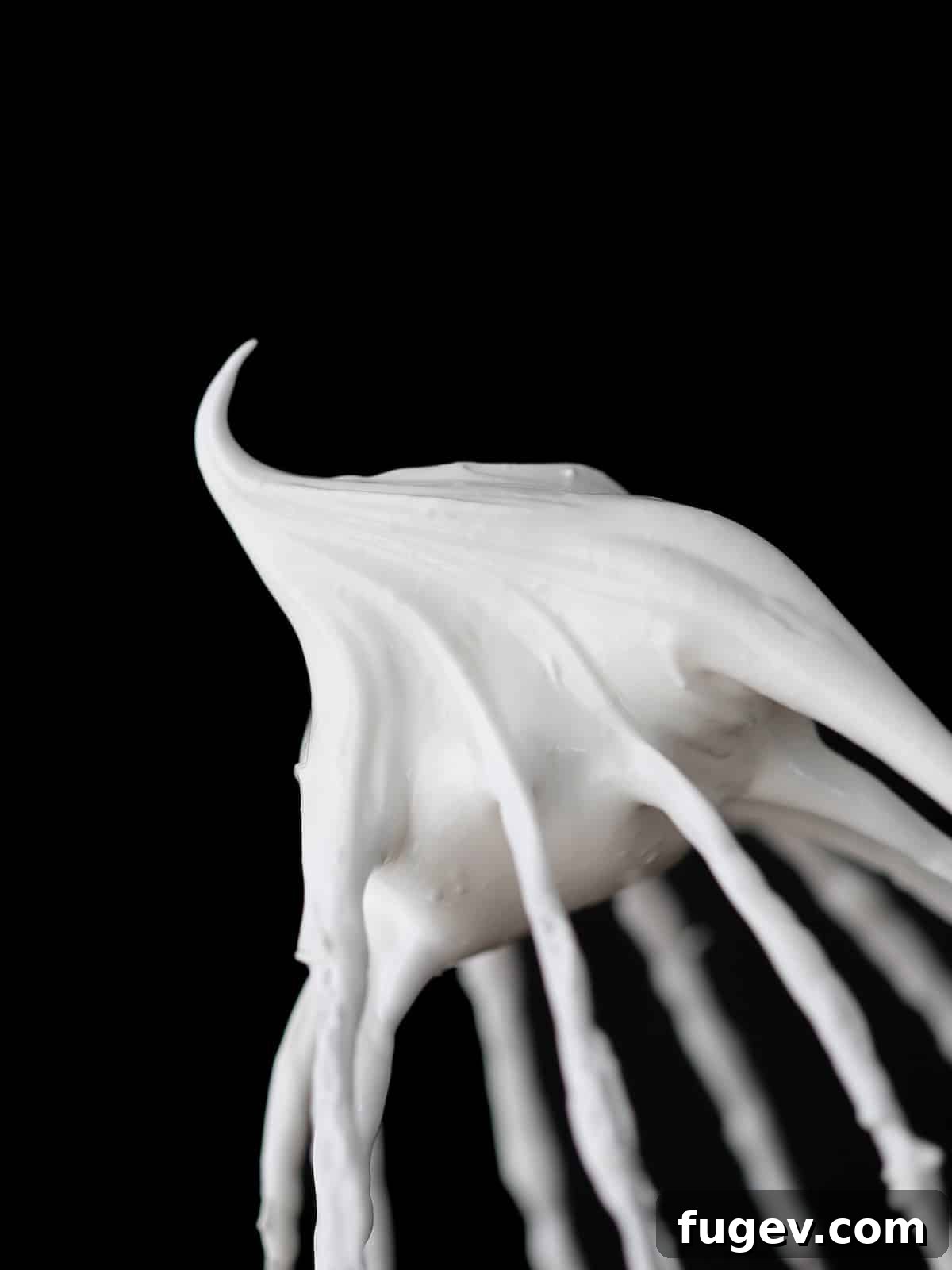 Whipped Marshmallow Dream 2 white marshmallow fluff on whisk with black background.