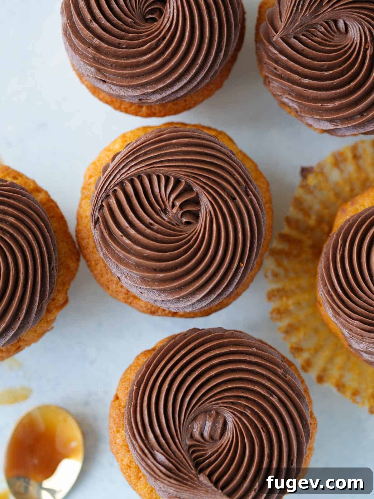 Gooey Chocolate Caramel Dreams 4 Elegant swirls of chocolate buttercream frosting adorn caramel cupcakes, set against a serene blue background, showcasing their irresistible beauty.