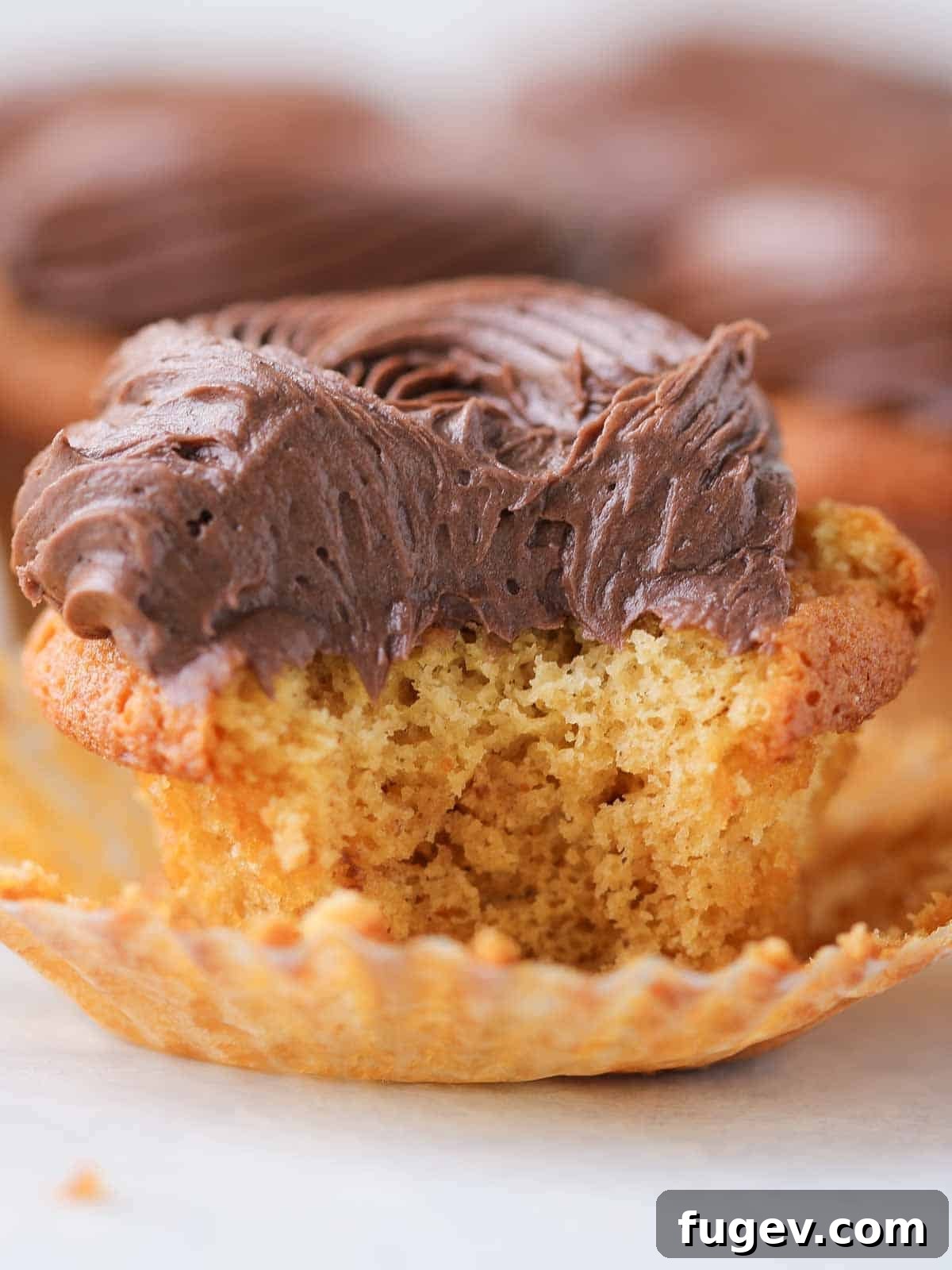 Gooey Chocolate Caramel Dreams 5 An unwrapped caramel cupcake, generously topped with smooth chocolate buttercream, promises a delightful culinary experience.
