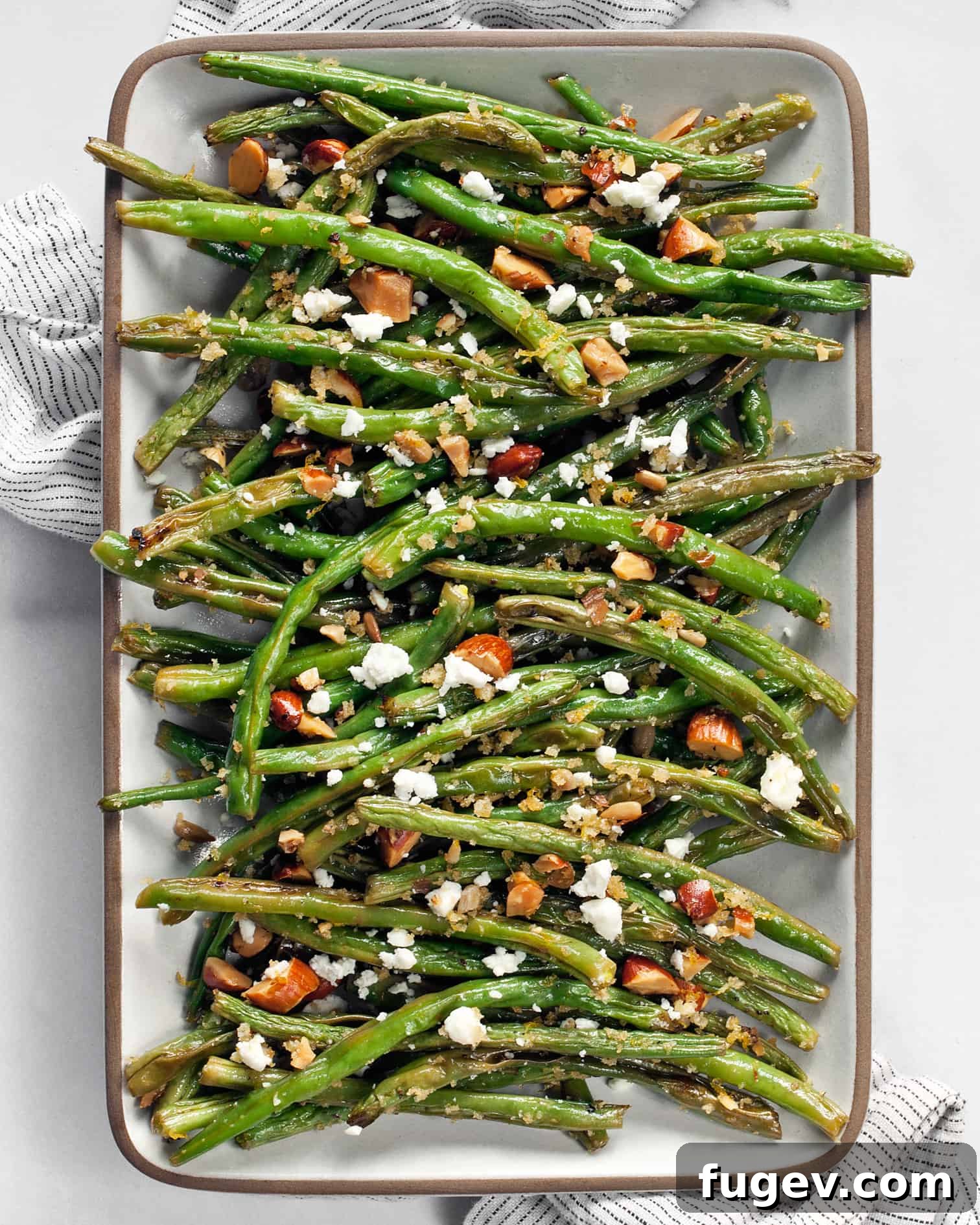 Almond Crusted Roasted Green Beans 6 A close-up of freshly roasted green beans generously topped with golden almond breadcrumbs and creamy feta, highlighting the intricate texture and vibrant colors of the dish.