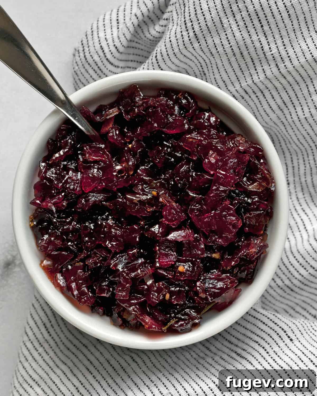 Artisan Sweet Onion Preserve 2 A bowl of rich, dark homemade onion jam with a spoon resting in it, ready to be served.