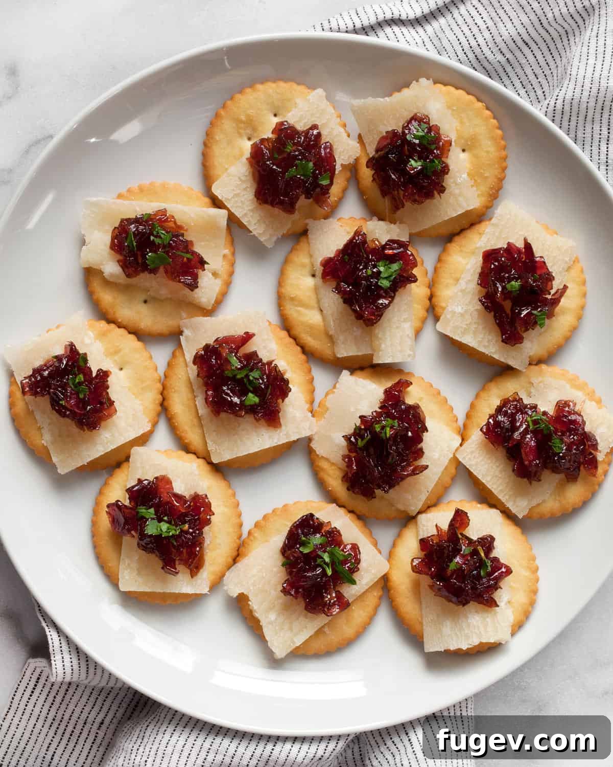 Artisan Sweet Onion Preserve 7 A plate of crackers topped with slices of Parmesan cheese and dollops of savory homemade onion jam.