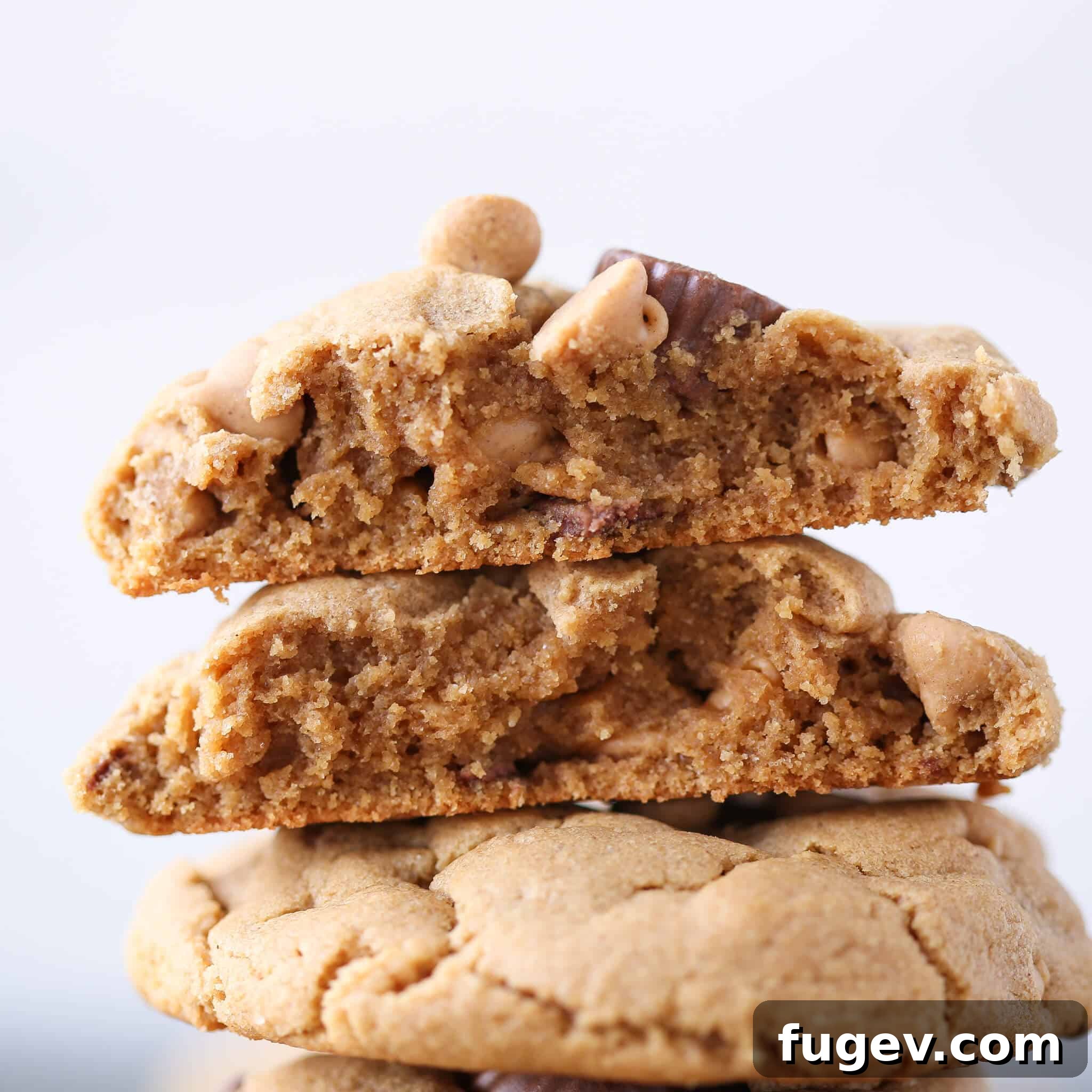 Irresistible Reese's Peanut Butter Cookies 3 A Reese's Peanut Butter Cookie broken in half, revealing its soft, chewy interior studded with mini Reese's Cups and peanut butter chips.