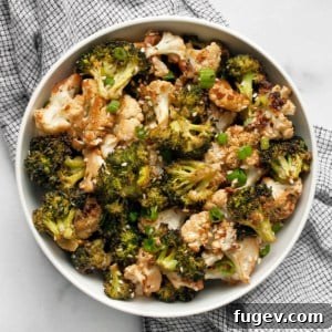 A bowl of freshly roasted tahini cauliflower and broccoli, garnished.