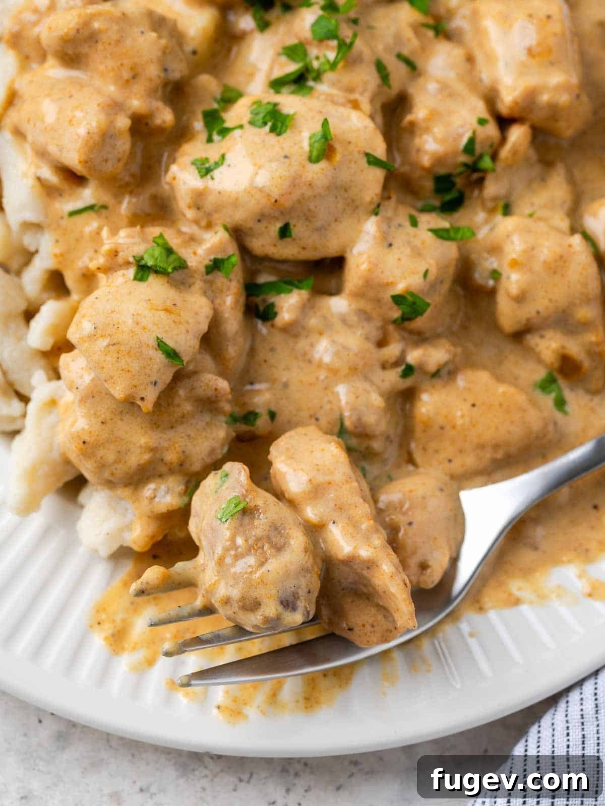 Grandma's Hungarian Chicken Paprikash 2 A fork holding a bite of creamy chicken paprikash with spaetzle, showing the rich sauce and tender chicken.