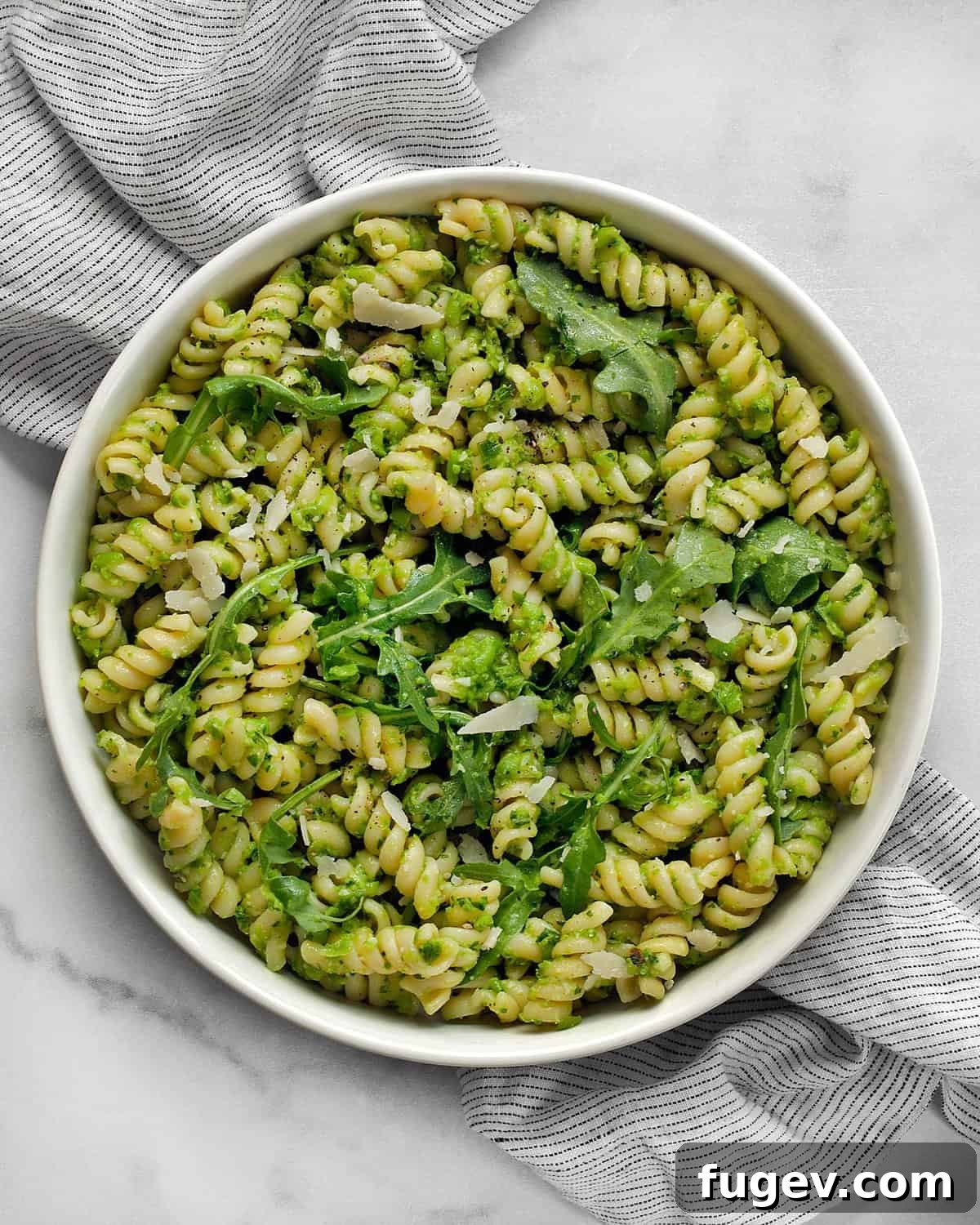 Emerald Green Pea Pesto Pasta 2 A beautifully plated bowl of vibrant green pea pesto pasta, garnished with fresh herbs and grated Parmesan cheese.