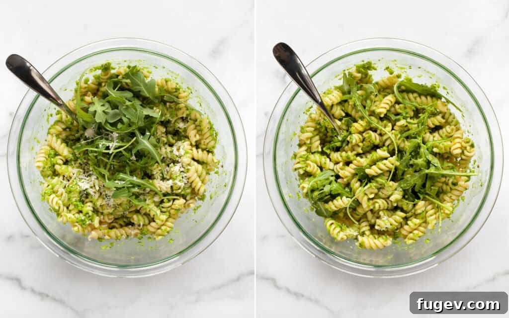 Emerald Green Pea Pesto Pasta 6 A large bowl of pea pesto fusilli pasta with fresh arugula and grated Parmesan being stirred in.