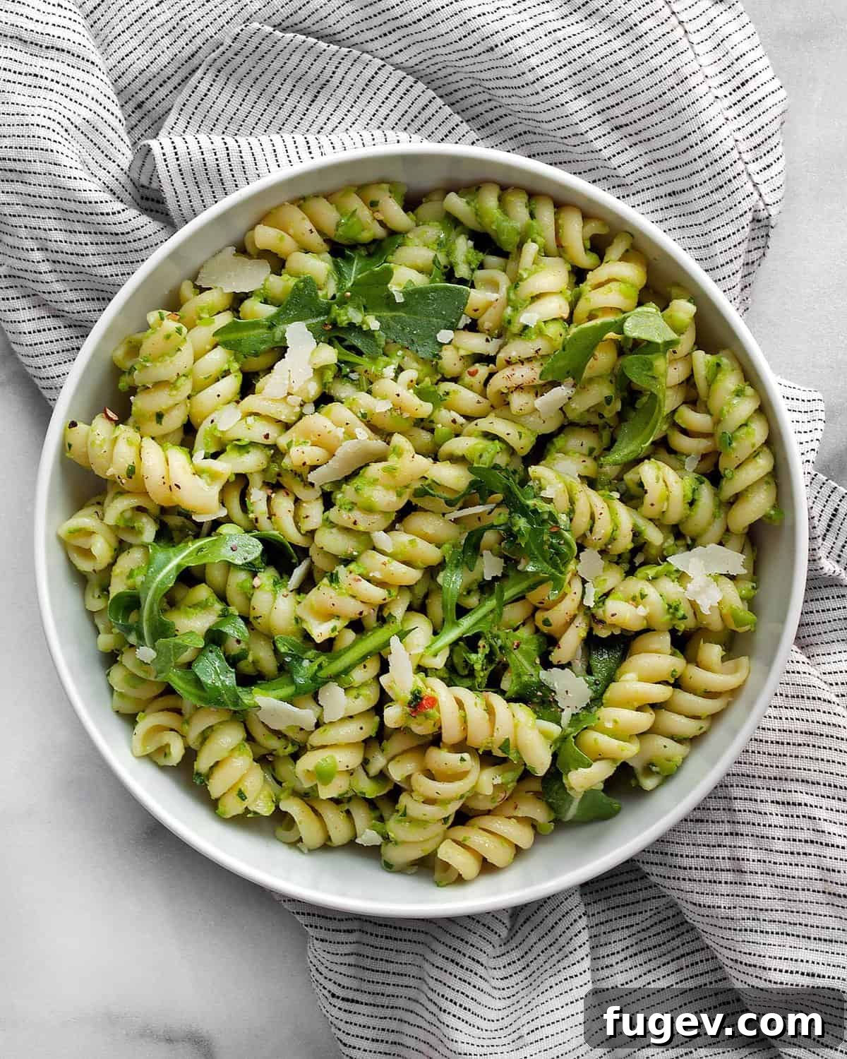 Emerald Green Pea Pesto Pasta 7 A close-up of vibrant pea pesto pasta in a rustic white bowl, showcasing its fresh green color and enticing texture.